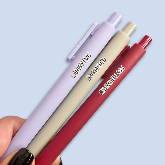Three pens with sayings on them. "LAHWYTMC"(lavender pen), "BAGGACOTD" (grey pen), "STFUATTDLAGG" ( dark red pen).