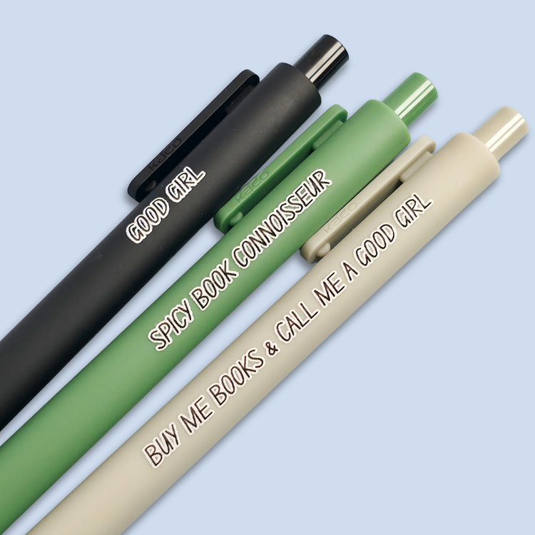 Three pens with quotes. "Good Girl" on a Black pen, "Spicy Book Connoisseur" on a green pen, and "Buy me books and call me a good girl" on a grey pen.
