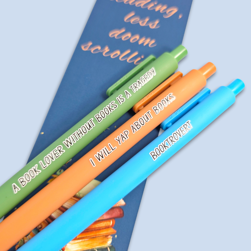 Three pens with book-themed text on a bookmark