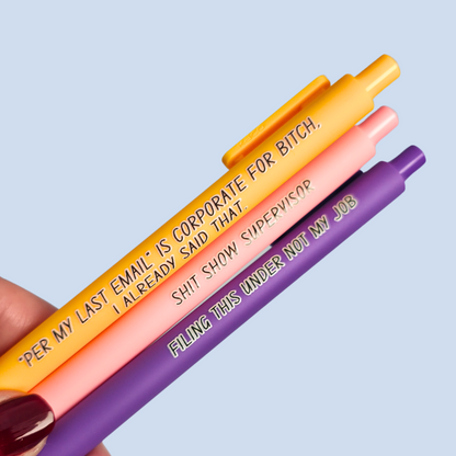 Three pens with sayings on them. "Per My Last Email" is Corporate for bitch, I already said that."(bright yellow pen), "Shit show supervisor" (pastel Pink pen), "Filing this under not my job" ( purple pen).