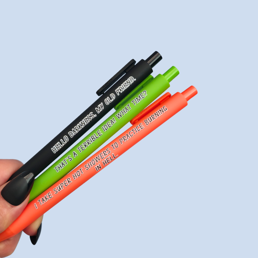 Three pens with quotes. "Hello darkness, my old friend." on a black pen, ' That's a terrible idea. What time?" on a lime green pen, and "I take super hot showers to practice burning in hell" on a orange pen.
