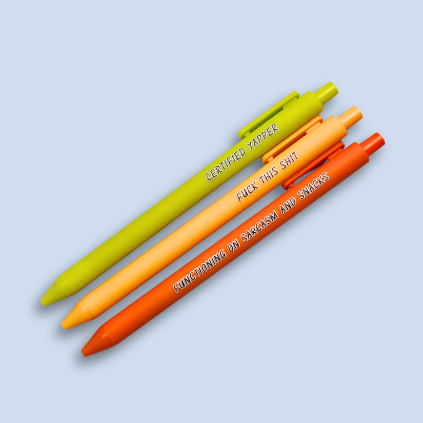 Three pens with sayings on them. "certified yapper" (lime green pen), "Functioning on sarcasm and snacks" (neon orange pen), "fuck this shit" (sunflower yellow pen).