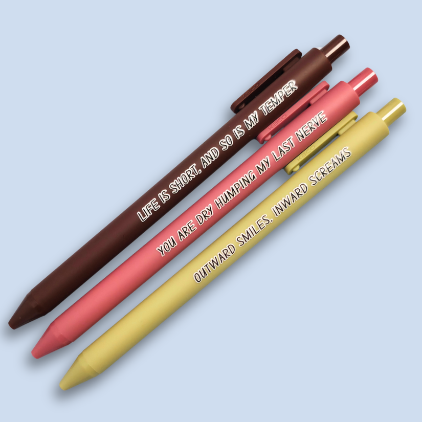 Three pens with humorous text on a light blue background. Text reads, "Life is short, and so is my temper" on a brown pen, "You are dry humping my last nerve" on a pink pen and "Outward smiles, inward screams" on a olive green pen