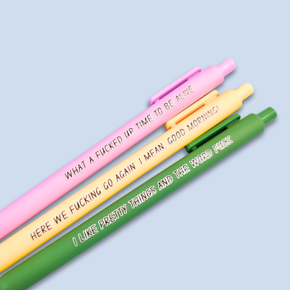Three pens with sayings on them. "here we fucking go again. I mean, Good morning!"(yellow pen), "What a fucked up time to be alive" (lilac pen), "I like pretty things and the word fuck" ( moss green pen)