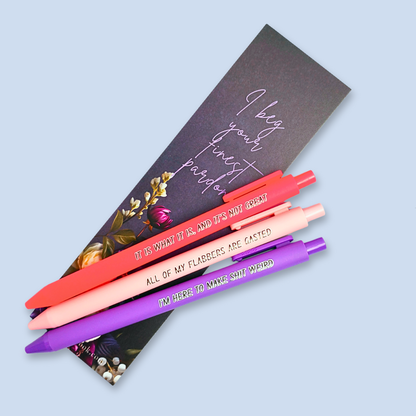 Three pens with sayings on them. "All of my flabbers are gasted" (pastel pink pen), "I'm here to make shit weird" (purple pen), "It Is what it is, and it's not great" ( neon pink pen).