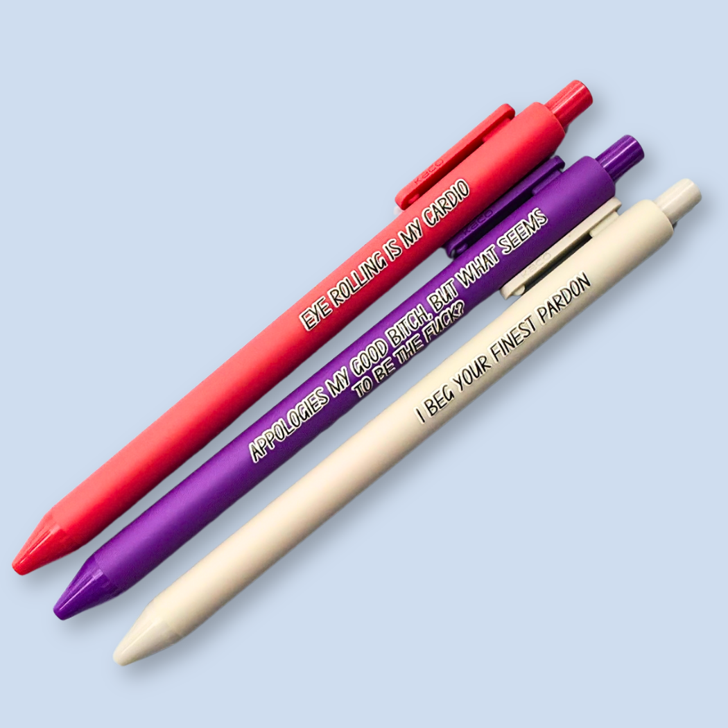 Three retractable gel pens in red, purple, and cream, arranged diagonally on a light blue background. Each pen features humorous text printed on the barrel.