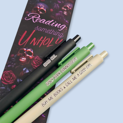 Three pens with quotes. "Good Girl" on a Black pen, "Spicy Book Connoisseur" on a green pen, and "Buy me books and call me a good girl" on a grey pen.