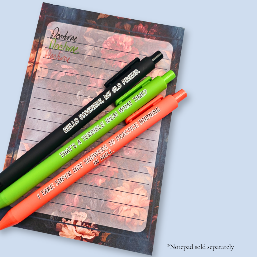 Three pens with quotes. "Hello darkness, my old friend." on a black pen, ' That's a terrible idea. What time?" on a lime green pen, and "I take super hot showers to practice burning in hell" on an orange pen. The pens rest on a notepad, with a sample ot the ink colors. Notepads are sold separately