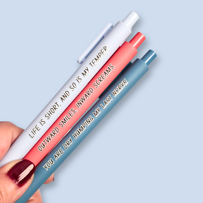 Three pens with humorous text on a light blue background. Text reads, "Life is short, and so is my temper" on a pastel blue pen, "You are dry humping my last nerve" on a blue grey pen and "Outward smiles, inward screams" on a salmon pink pen