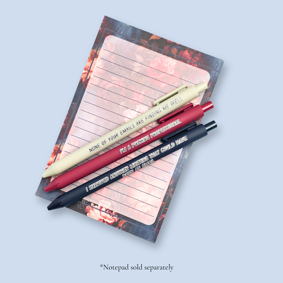 Three pens with quotes. "None of your emails are finding me well" on a grey pen, " I'm a fucking professional" on a dark red pen, and "I survived another meeting that could have been an email" on a navy blue pen.