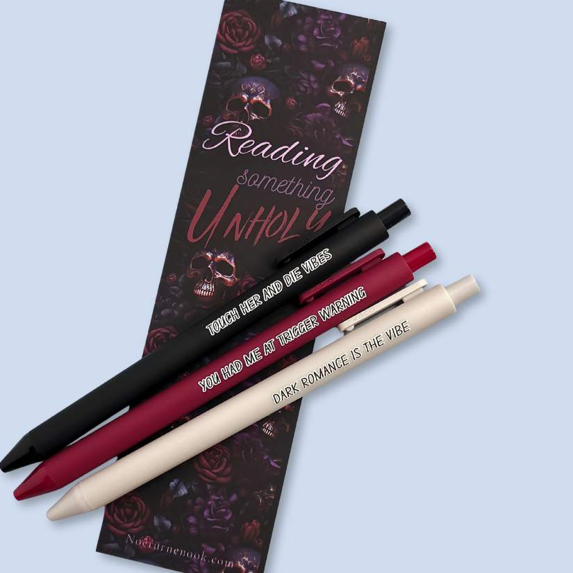 Three pens with sayings on them. "Dark romance is the vibe" (light grey pen), "You had me at trigger warning" (wine pen), "Touch her and die vibes" ( black pen).