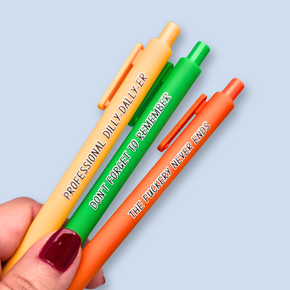 Three pens with humorous text on a light blue background. Text reads, "Professional Dilly-Dally-Er" on a yellow pen, "Don't forget to remember" on a green pen and "The fuckery never ends" on a orange pen