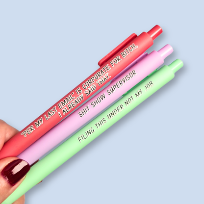 Three pens with sayings on them. "Per My Last Email" is Corporate for bitch, I already said that."(salmon pink pen), "Shit show supervisor" (lilac pen), "Filing this under not my job" ( pastel green pen).
