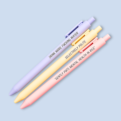 Three pens with humorous text on a light blue background. Text reads, "Gently puts mental health in rice" on a pastel pink pen, "Selectively polite" on a pastel yellow pen and "drink more fucking water" on a lavender pen