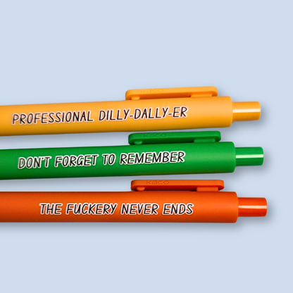 Three pens with humorous text on a light blue background. Text reads, "Professional Dilly-Dally-Er" on a yellow pen, "Don't forget to remember" on a green pen and "The fuckery never ends" on a orange pen