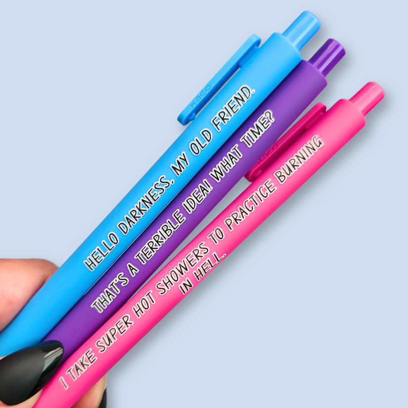 Three pens with quotes. "Hello darkness, my old friend." on a bright blue pen, ' That's a terrible idea. What time?" on a purple pen, and "I take super hot showers to practice burning in hell" on a hot pink pen.