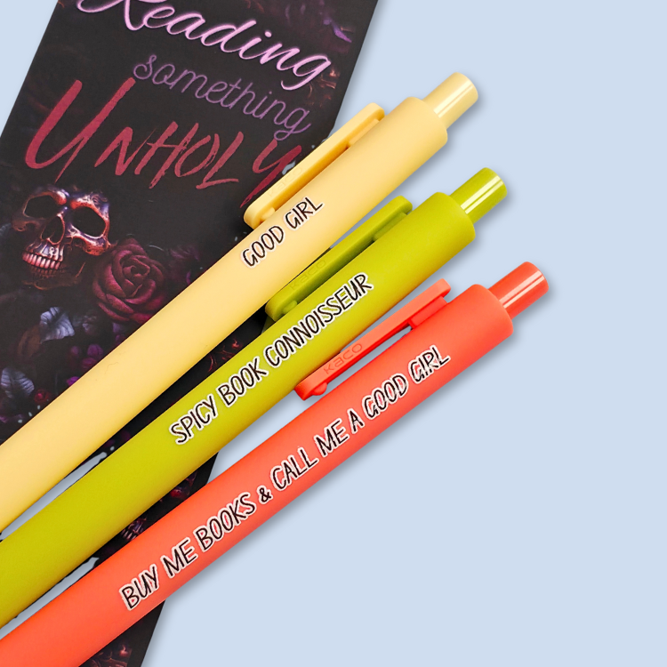 Three pens with quotes. "Good Girl" on a yellow pen, "Spicy Book Connoisseur" on a neon green pen, and "Buy me books and call me a good girl" on a neon orange pen.