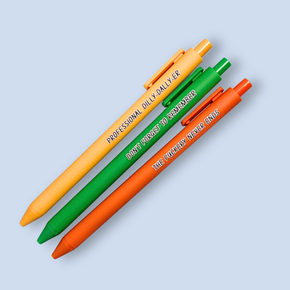Three pens with humorous text on a light blue background. Text reads, "Professional Dilly-Dally-Er" on a yellow pen, "Don't forget to remember" on a green pen and "The fuckery never ends" on a orange pen