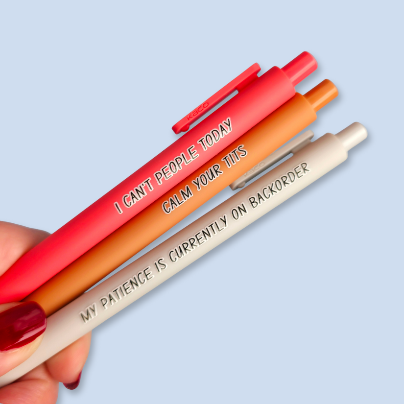 Three colorful pens held by a hand with a light blue background. Pens read: CALM YOUR TITS (this pen is lime orange), I CAN'T PEOPLE TODAY (this pen is Dark Pink), and MY PATIENCE IS CURRENTLY ON BACKORDER (this pen is light grey)