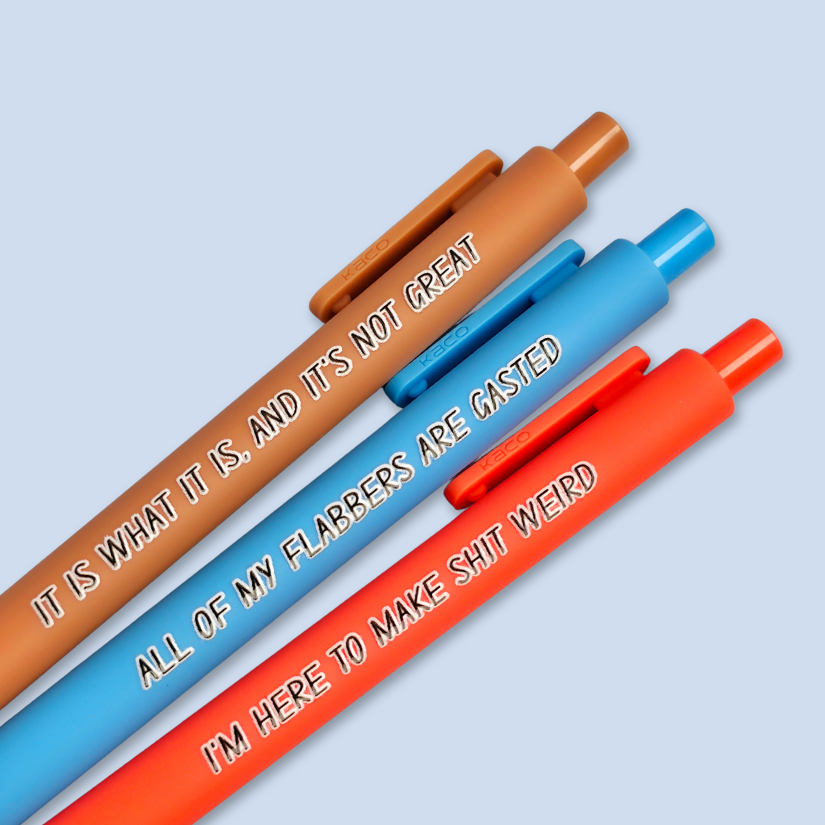 Three pens with sayings on them. "All of my flabbers are gasted" (bright blue pen), "I'm here to make shit weird" (neon orange pen), "It Is what it is, and it's not great" ( caramel pen).