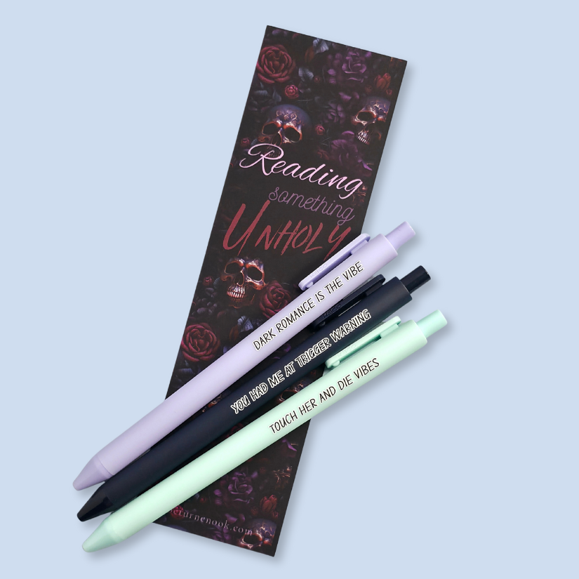 Three pens with sayings on them. "Dark romance is the vibe" (lavender pen), "You had me at trigger warning" (black pen), "Touch her and die vibes" ( mint pen).