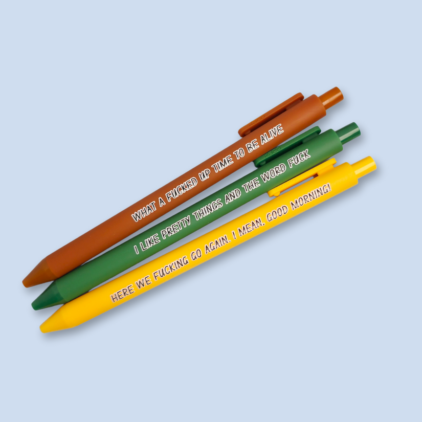 Three pens with sayings on them. "here we fucking go again. I mean, Good morning!"(bright yellow pen), "What a fucked up time to be alive" (sienna pen), "I like pretty things and the word fuck" ( green pen)