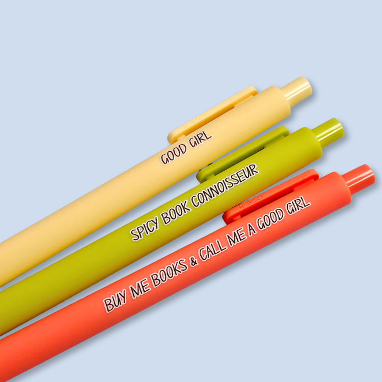 Three pens with quotes. "Good Girl" on a yellow pen, "Spicy Book Connoisseur" on a neon green pen, and "Buy me books and call me a good girl" on a neon orange pen.