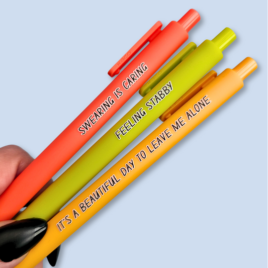 Three pens with sayings on them. "Feeling Stabby."(Lime pen), "It's a beautiful day to leave me alone" (Sunflower yellow pen), "Swearing is caring" ( neon orange pen).